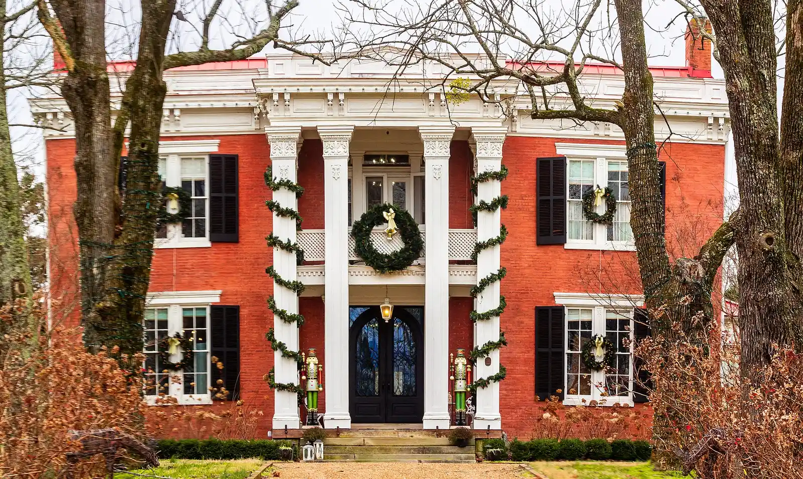 Mountview, a historic brick house in Brentwood, dressed for Christmas with garland on its columns and wreaths in the windows