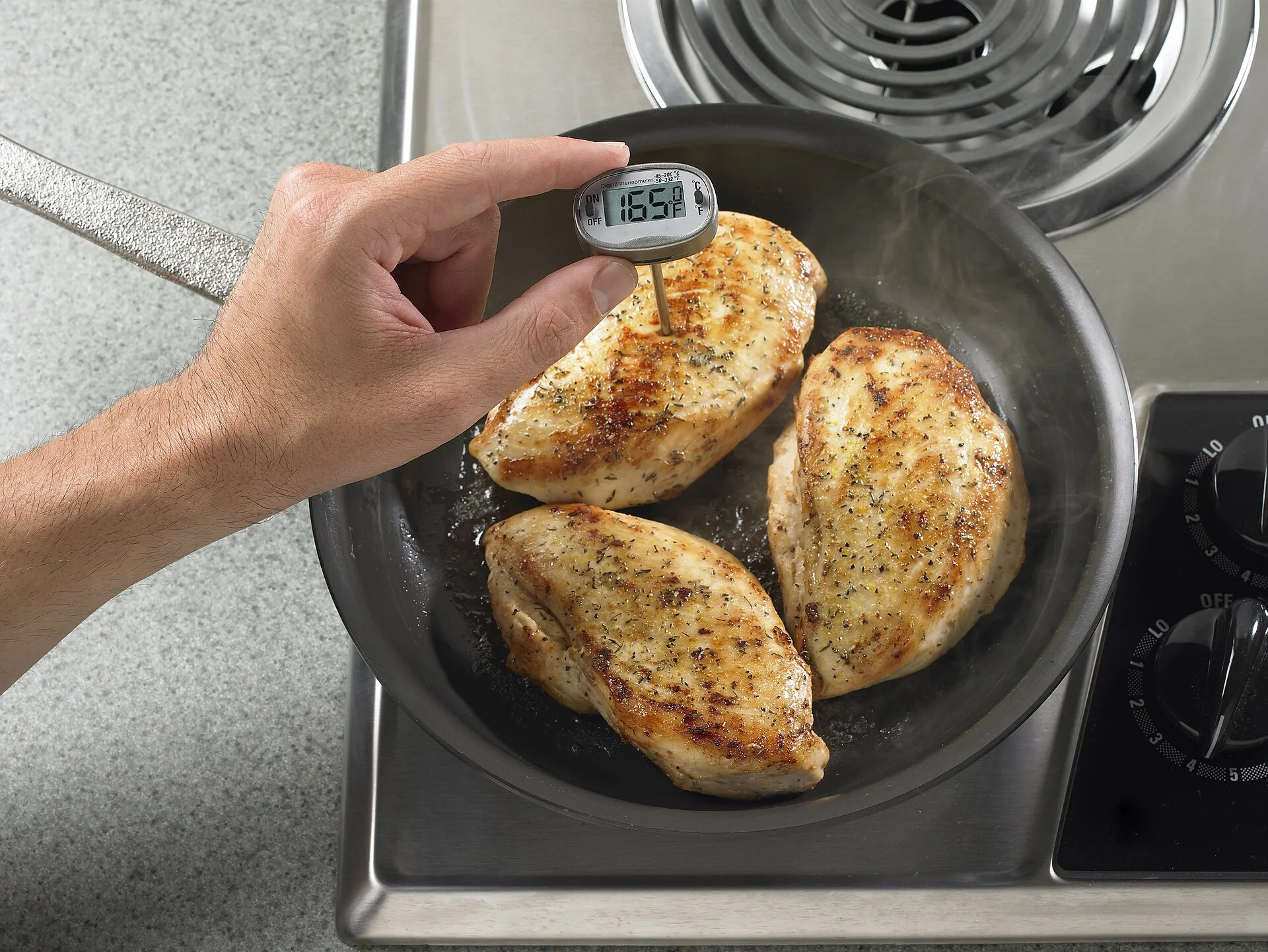 A cook checks the internal temperature of chicken with a food thermometer. Food temperatures are among the items Tennessee inspectors record.