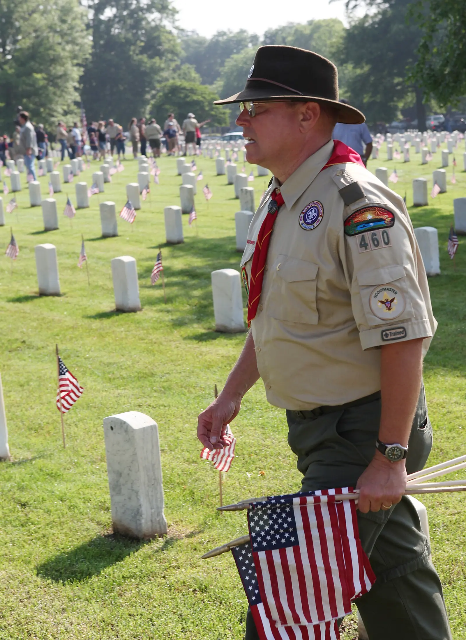 A Boy Scout leader carries small flags to place on graves before Memorial Day at Nashville National Cemetery in Madison