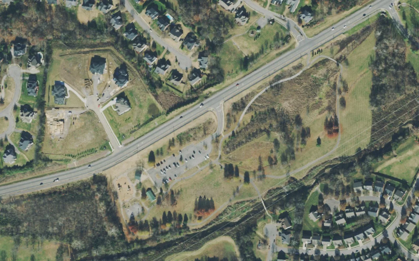 Owl Creek Park beside Concord Road in east Brentwood, with its playground, shelter, parking lot and paths, and houses on both sides of the road, seen from the air.