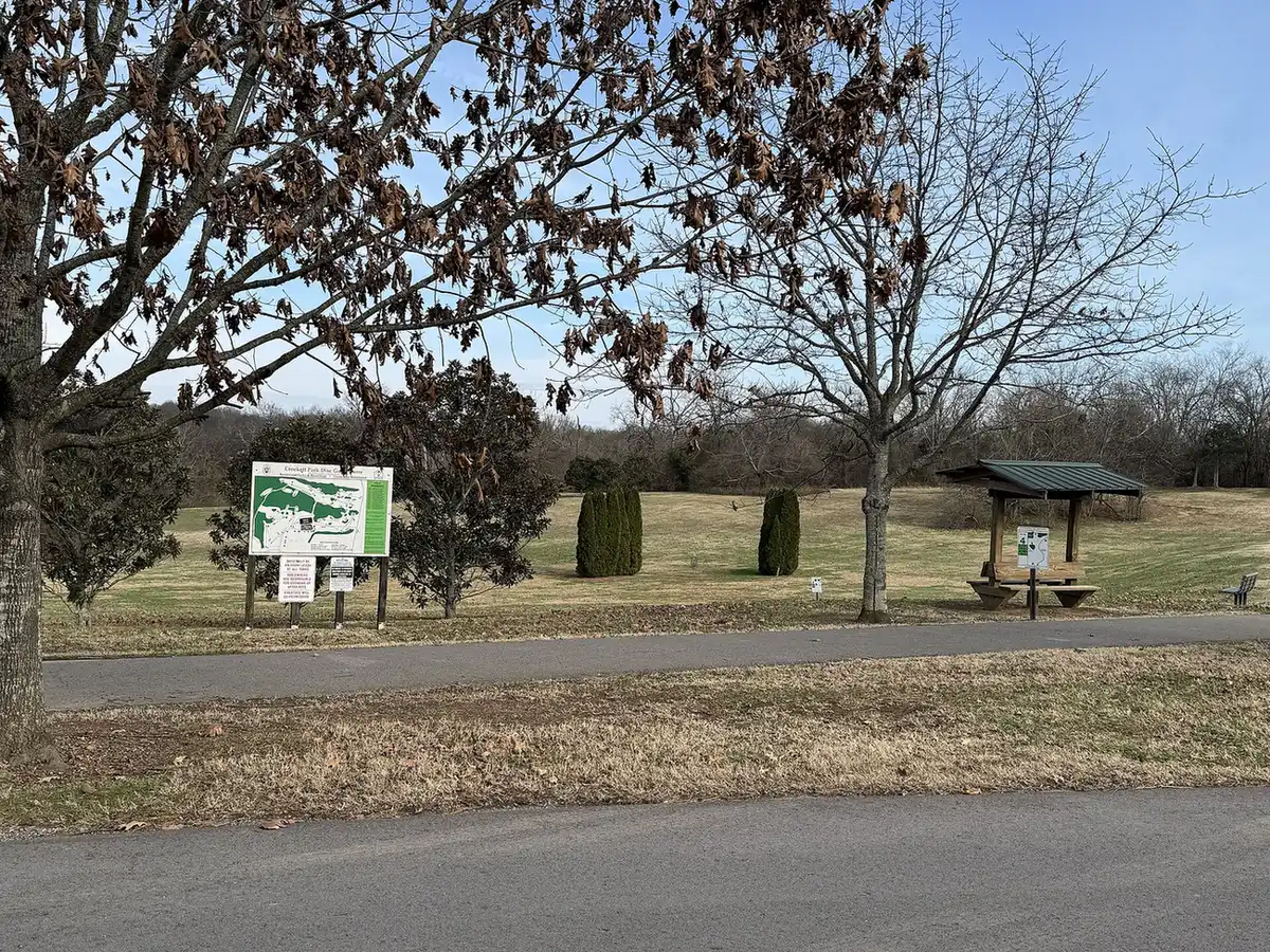 The disc golf course sign, a shelter and a paved path in Crockett Park in Brentwood